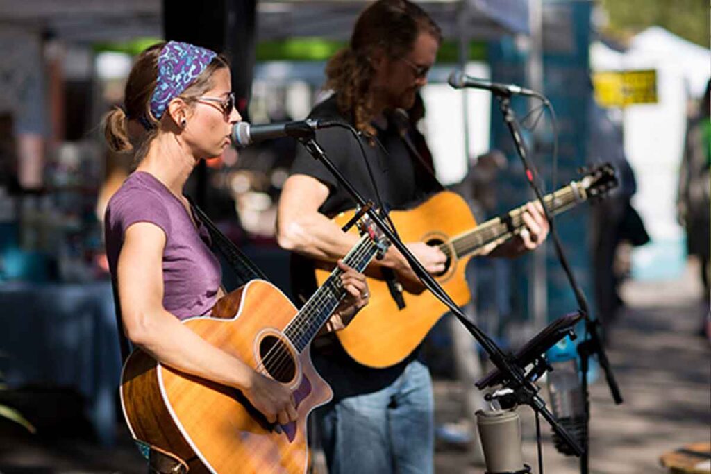 Two musicians singing and playing guitars at the bradenton market