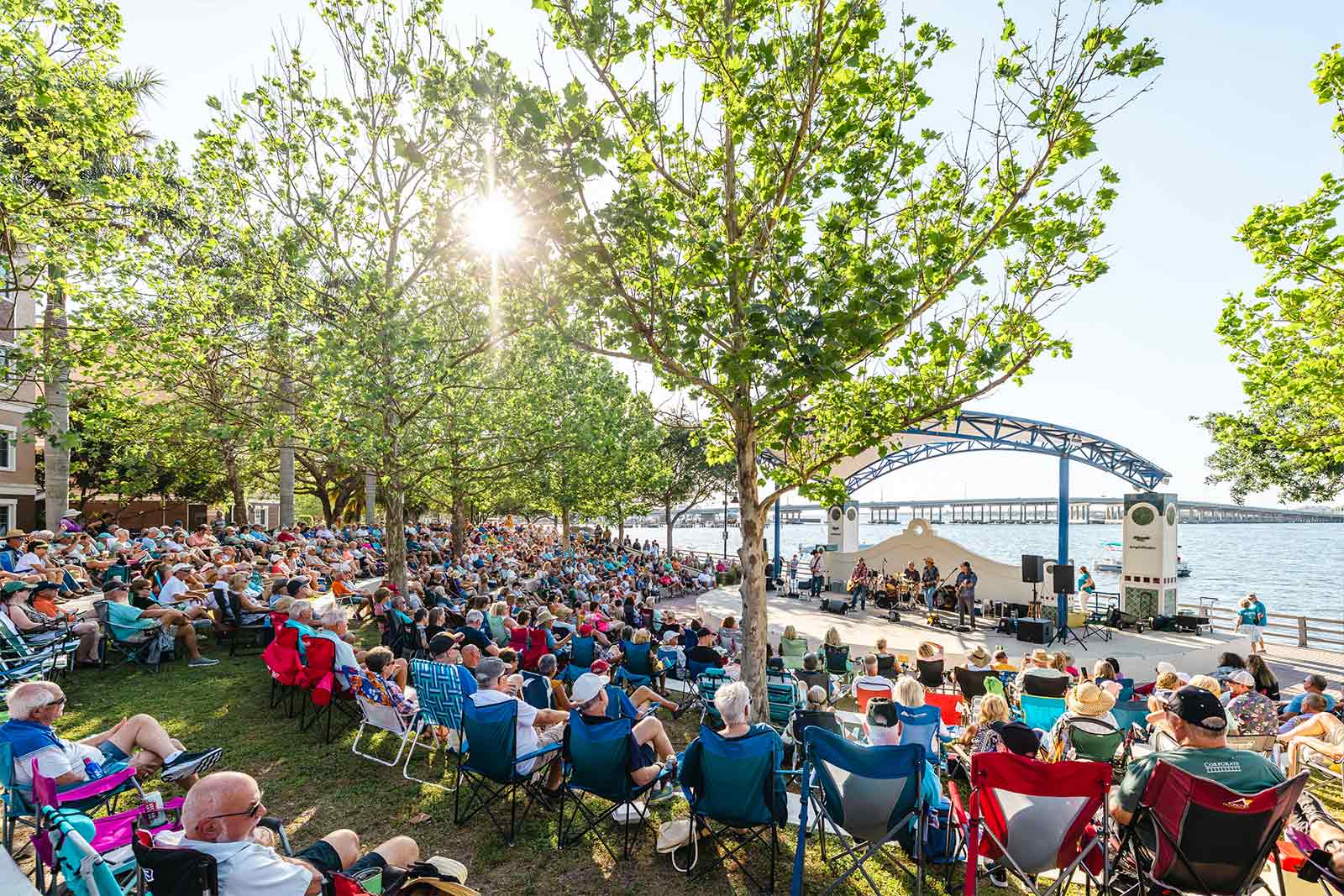 people sitting at the amphitheater at the riverwalk listening to musicians