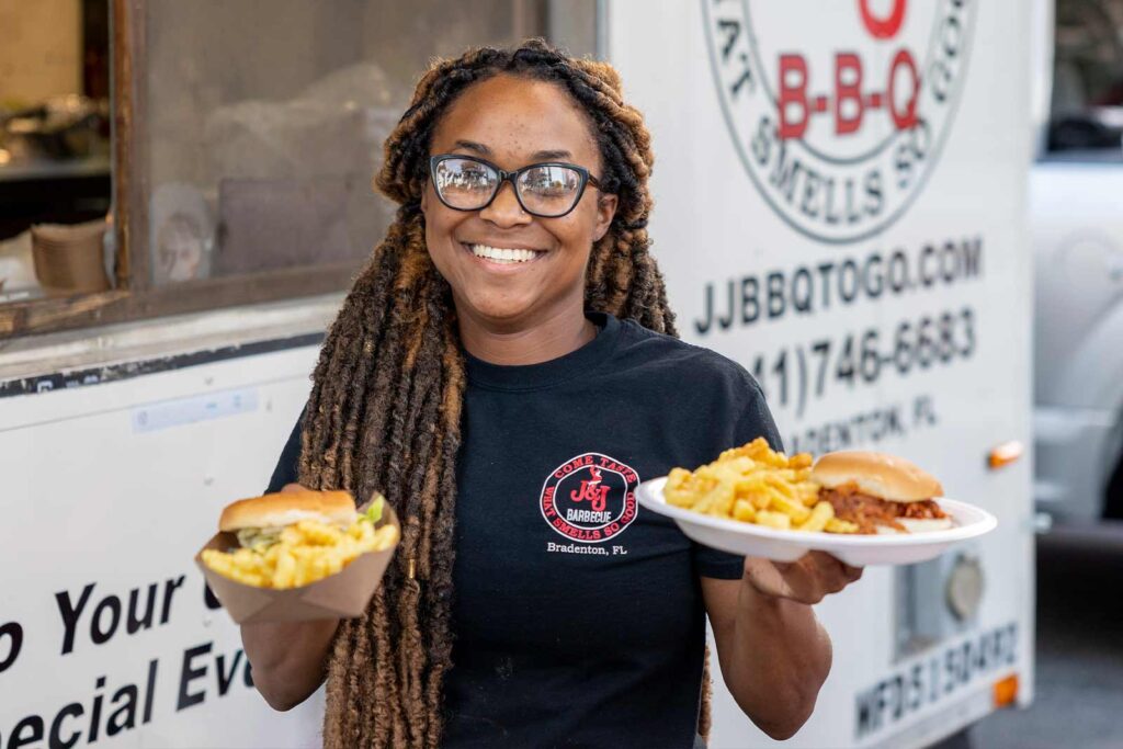 woman with glasses holding two plates of food at an event