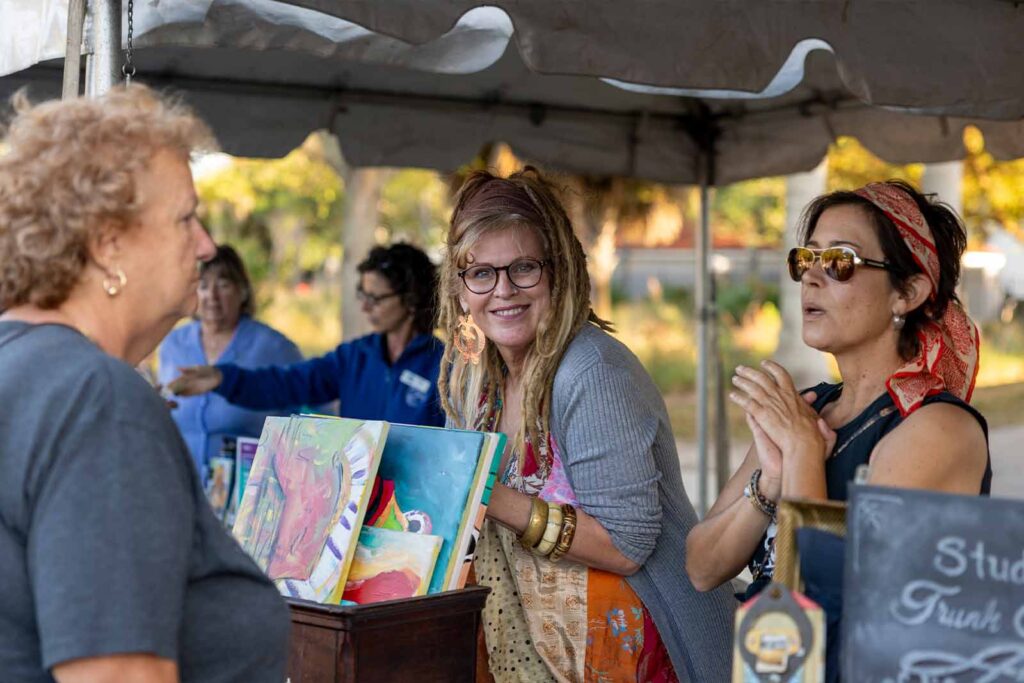 vendor smiling at camera while other vendor talks with patron