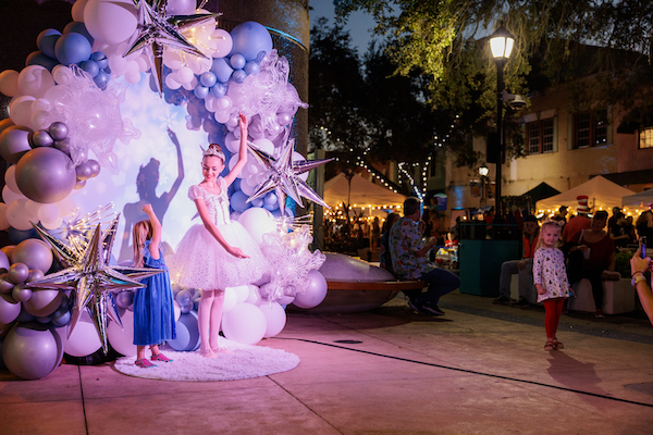 Young ballerina posing in front of balloon arch and a child mimics her pose during Winter Wonderland