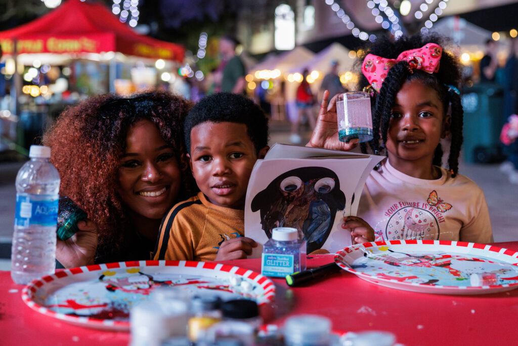 Woman and two young children smile while at a table with art supplies during Winter Wonderland